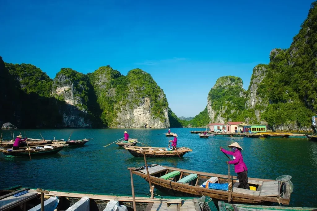 personas navegando en canoas en el mar, rodeada de montañas rocosas en asia.