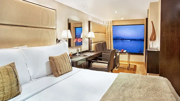 el crucero the oberoi en Egipto cuenta con una habitación con una amplia cama para dos personas, un escritorio con espejo y dos sillas con mesa para que disfrutes de tus comidas mientras ves el mar