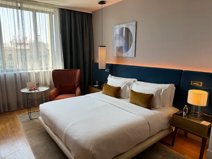 habitación perfecta para parejas, con un acogedor sillón y un gran ventanal que ofrece vistas panorámicas de la ciudad. El lugar ideal para relajarse y disfrutar de la vista desde la comodidad de tu habitación.