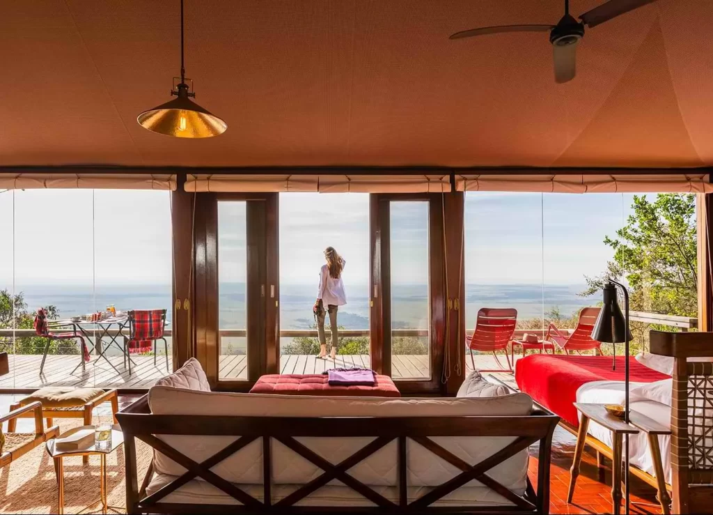 mujer turista alojada en una amplia habitación donde esta disfrutando de la vista en el balcón