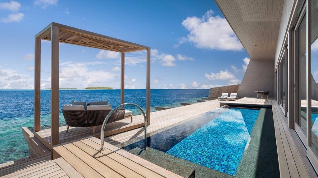 piscina con vista al mar con sillas de madera
