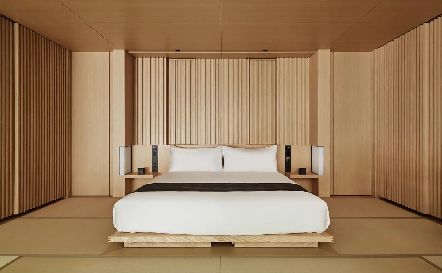 lujosa habitación en Tokio, con un estilo moderno, con cama para dos personas, nochero y lampara incorporada.