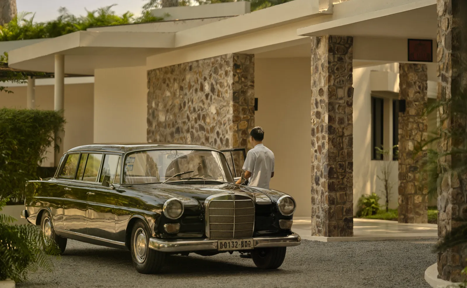 personal abriendo la puerta de un carro, estacionado frente a un elegante hotel.