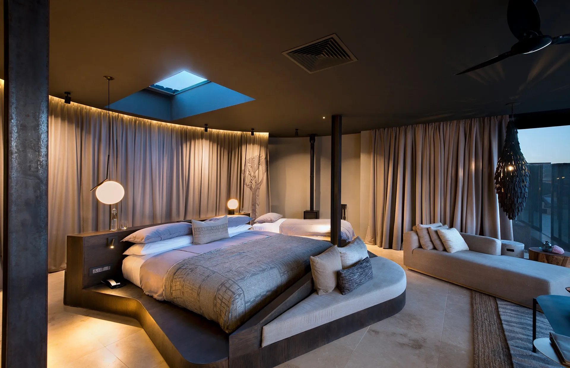 lujosa habitación con aire acondicionado, con cama para dos personas y una cama individual, un sillón y un ventanal grande para disfrutar de la vista