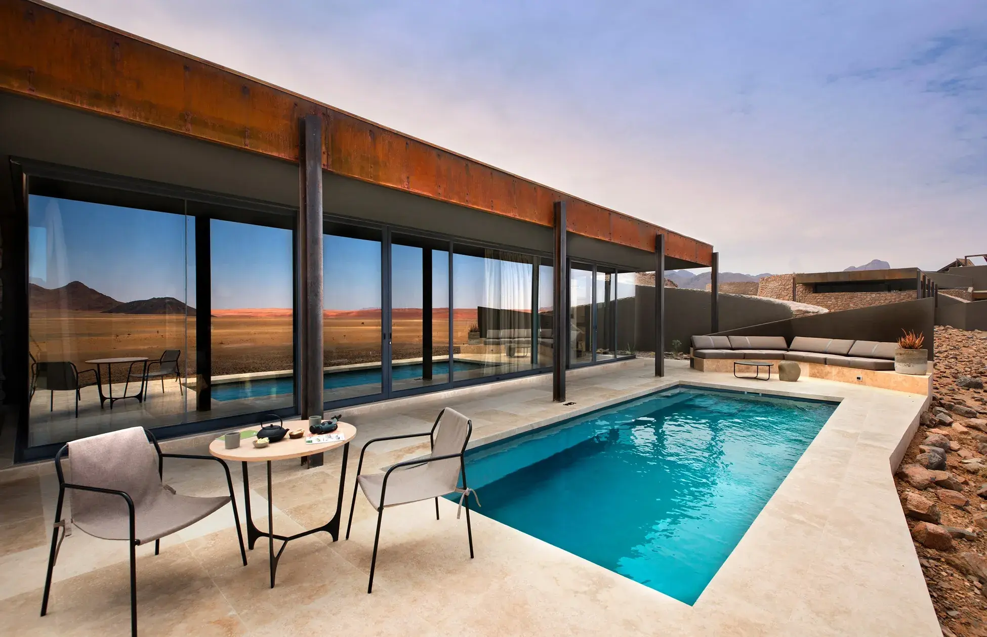 piscina al aire libre con sillas y mesa para desayunar al aire libre con vista al desierto.