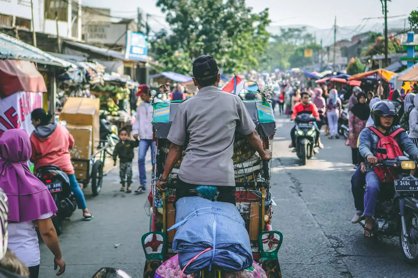 personas caminando y en moto recorriendo las plazas de Bali.