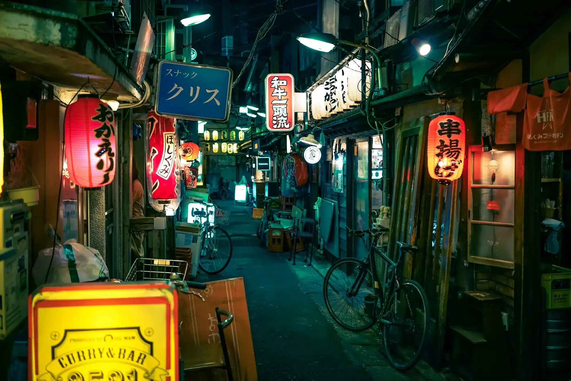 callejón iluminado en la noche con puestos de comida japonesa.