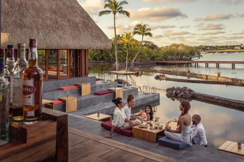 turista desayunando en el Four Seasons Resort Mauritius en Anahita rodeado de jardines tropicales