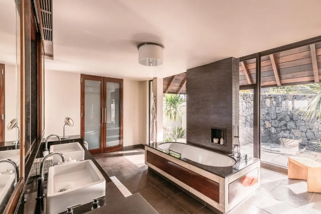 baño de lujo con tina, dos lava manos y una puerta de vidrio donde se puede salir al patio