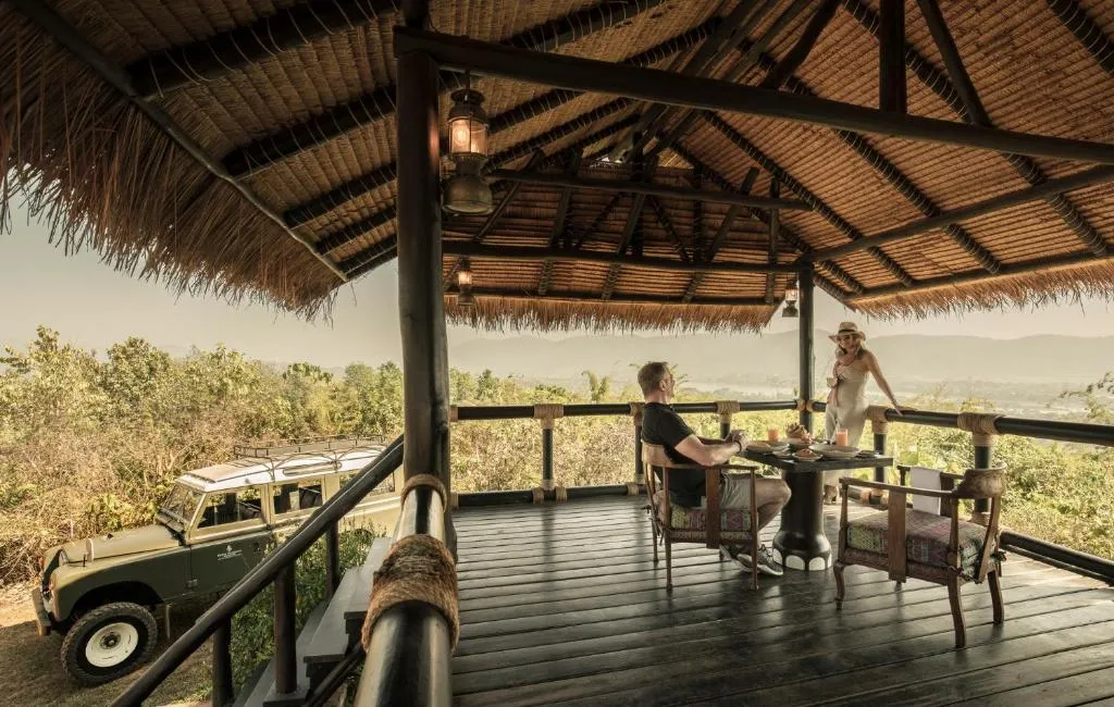 dos turistas en el balcón disfrutando de un desayuno y de una hermosa vista del safari