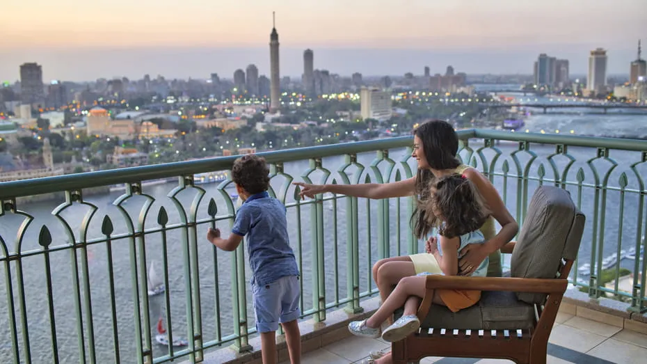 turistas sentadas en una silla en el balcón mirando el mar y la ciudad