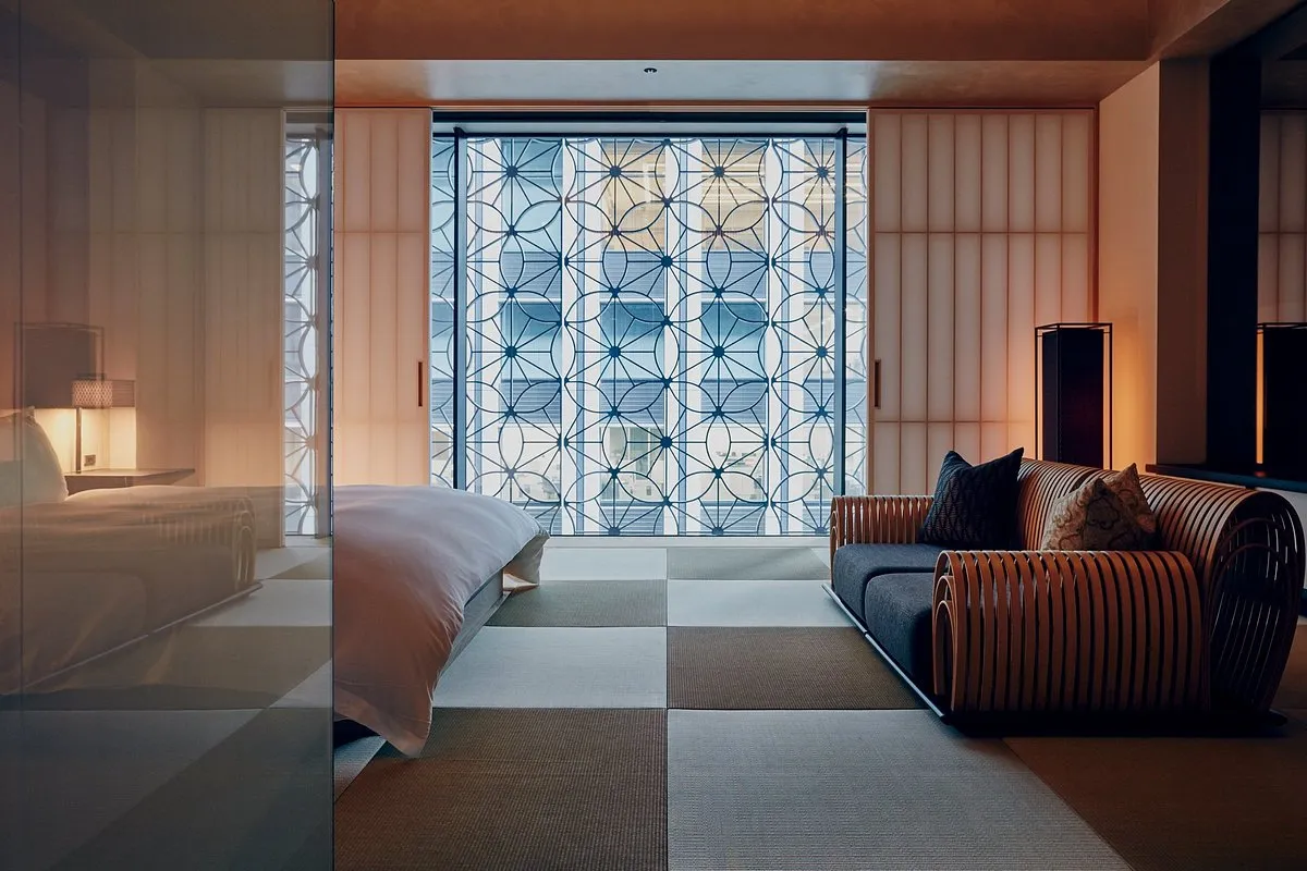 el hotel hoshinoya cuenta con una habitación amplia con cama para dos personas, asientos y un ventanal grande con vista a la ciudad.
