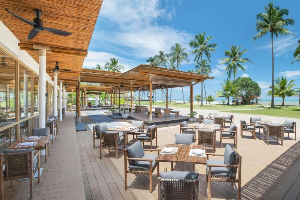 restaurante del JW Marriott Khao Lak Resort & Spa al aire libre, cuenta con mesas y sillas cómodas para disfrutar de un delicioso desayuno y de una gran vista.