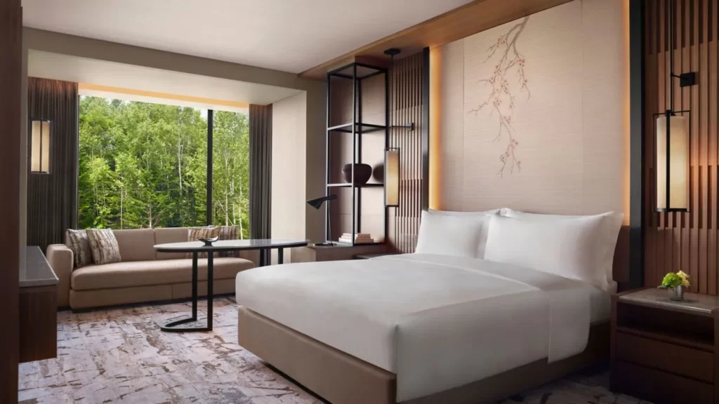 habitación con cama para dos personas, una mesa decorativa, un sillón y un ventanal