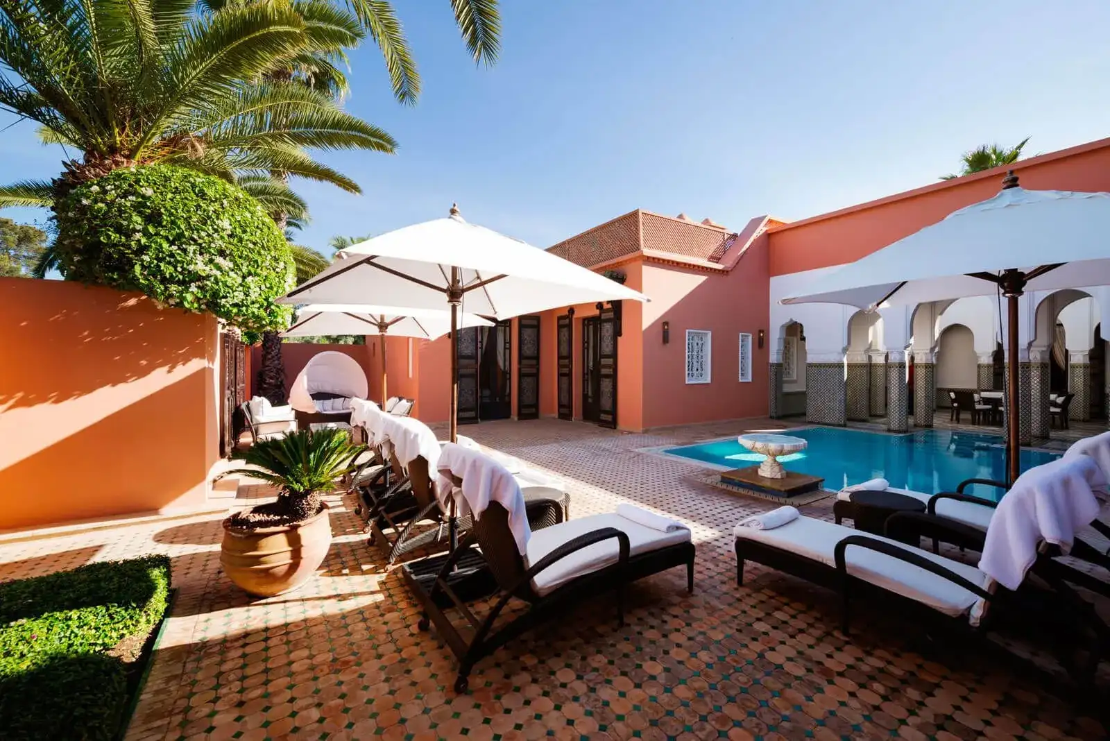 hotel con una piscina y sillas con sombrillas para asolearse y tener un día relajado