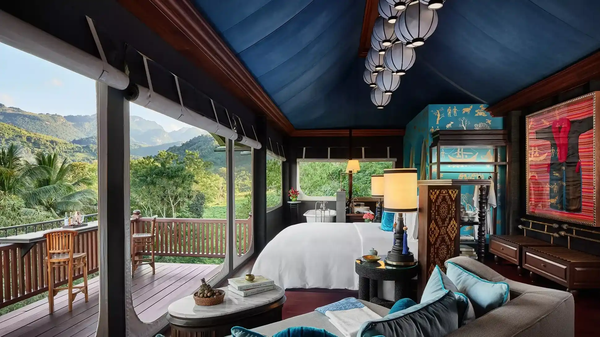 habitación grande de lujo con cama para dos personas, sala, un baño con tina y un balcón con una espectacular vista.