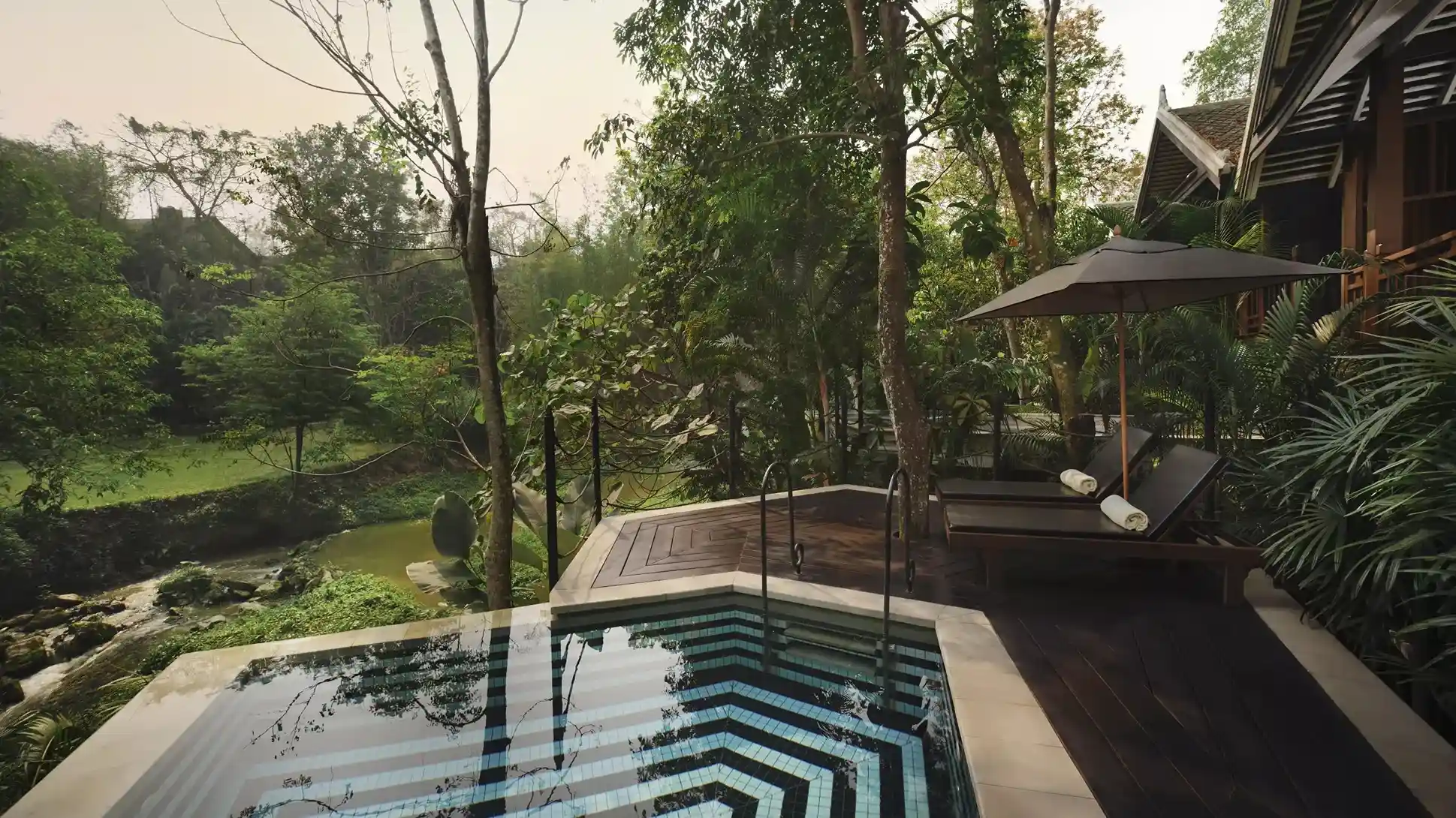 zona de piscina privada con asientos de descanso rodeada de arboles y zona verde para un ambiente mas agradable.