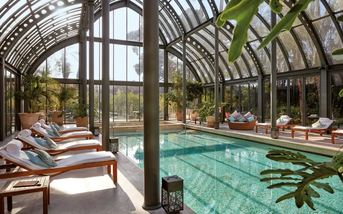 zona de piscina con ventanales y puertas de vidrio con sillas para acostarse y plantas para un lugar mas fresco.