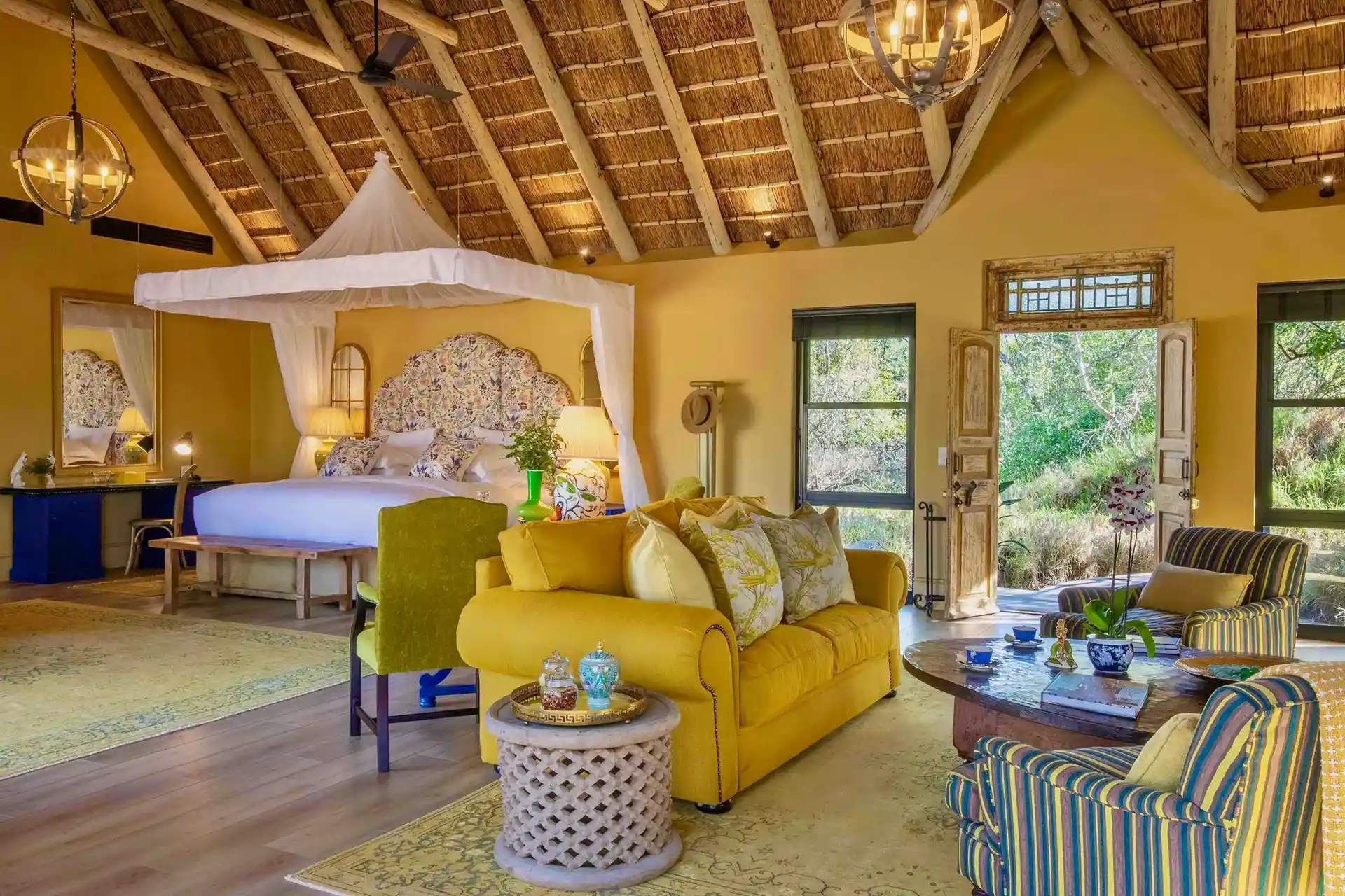 habitación de lujo con cama para dos personas, escritorio con espejo y una sala con sillones para una cómoda estadía