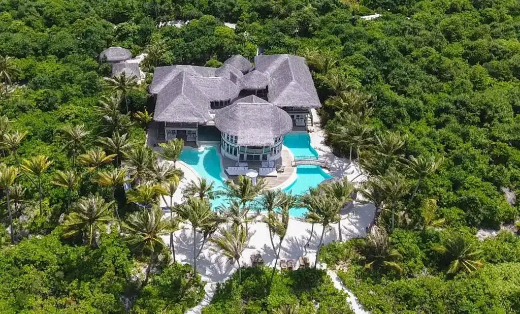 hotel de lujo en Soneva Jani con piscina privada, paso a la playa rodeada de palmeras y zona verde.