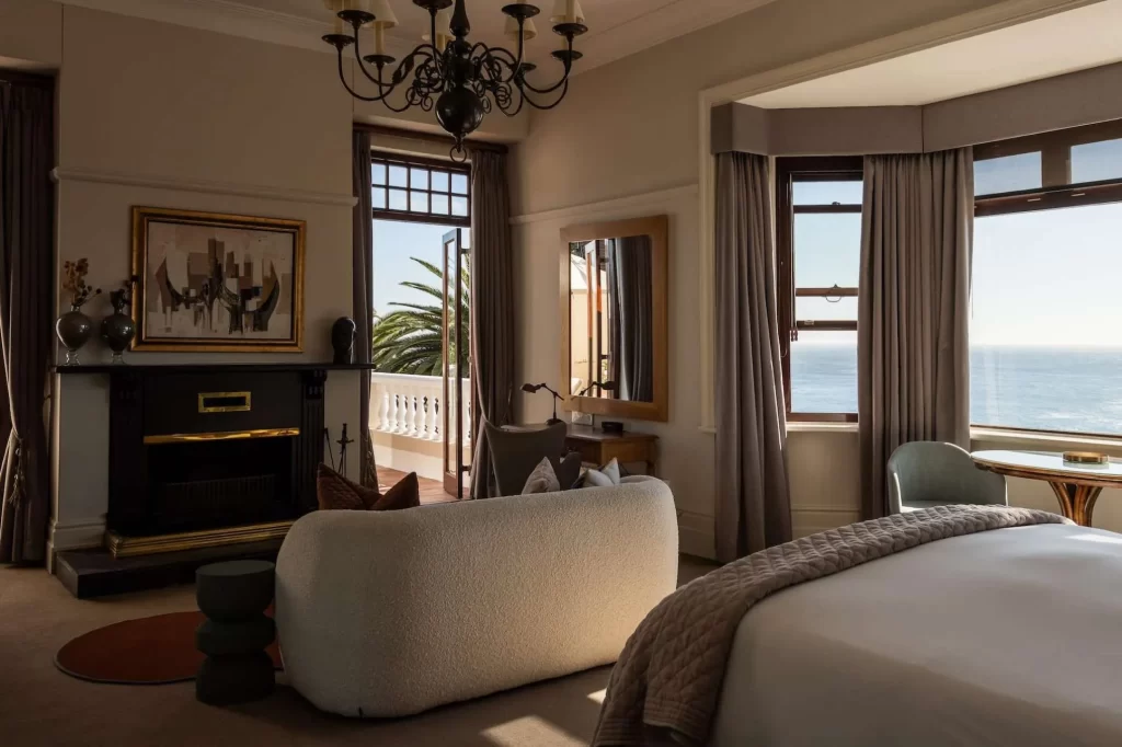 lujosa casa con una amplia habitación, sillón, una mesa con sillas y un gran ventanal para que puedas disfrutar de una vista al mar mientras desayunas