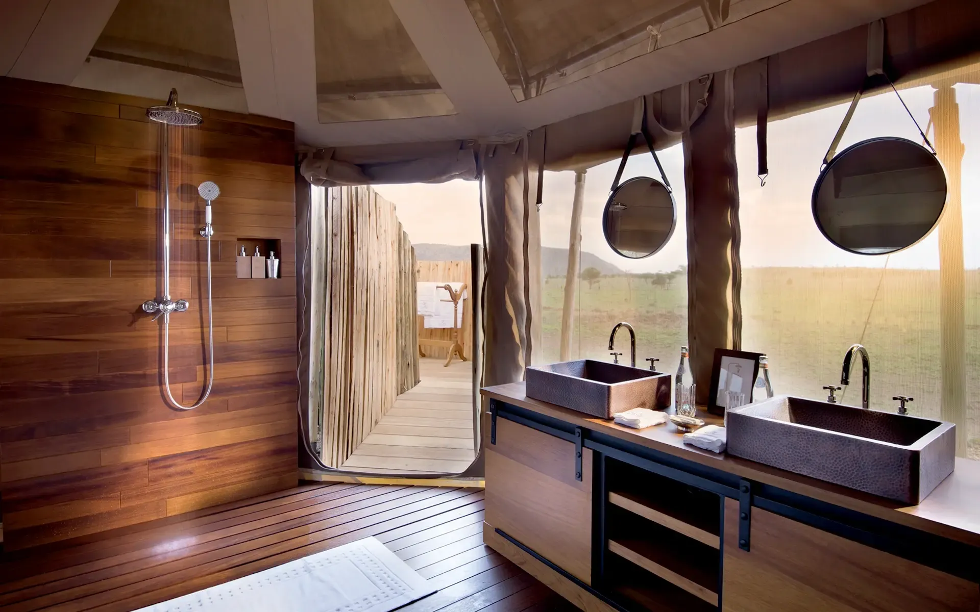 ducha de lujo, espacio amplio y abierto, con una iluminación, con dos elegantes fregaderos y un ventanal que ofrece una vista de la sabana africana