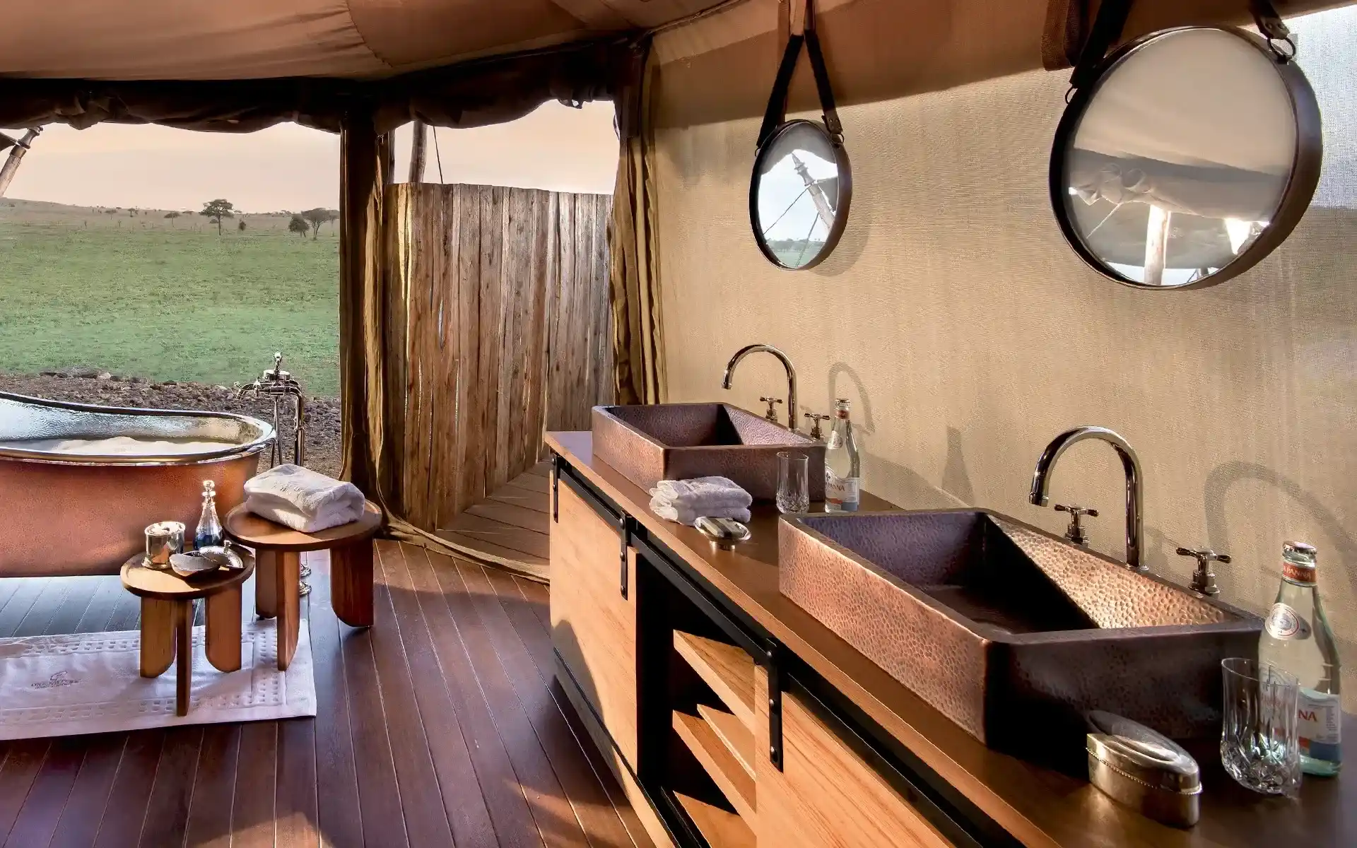 ducha de lujo con tina, espacio amplio y abierto, con dos elegantes fregaderos y un ventanal que ofrece una vista de la sabana africana