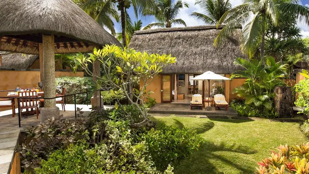suite con techo de paga rodeada de jardines tropicales dos sillas para estar al aire libre