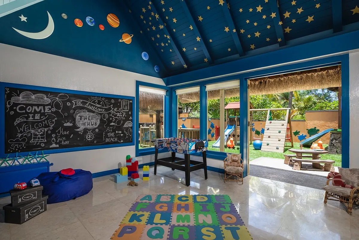zona para niños con diferentes juegos y una puerta grande con salida al jardín donde esta los columpios y las resbaladilla