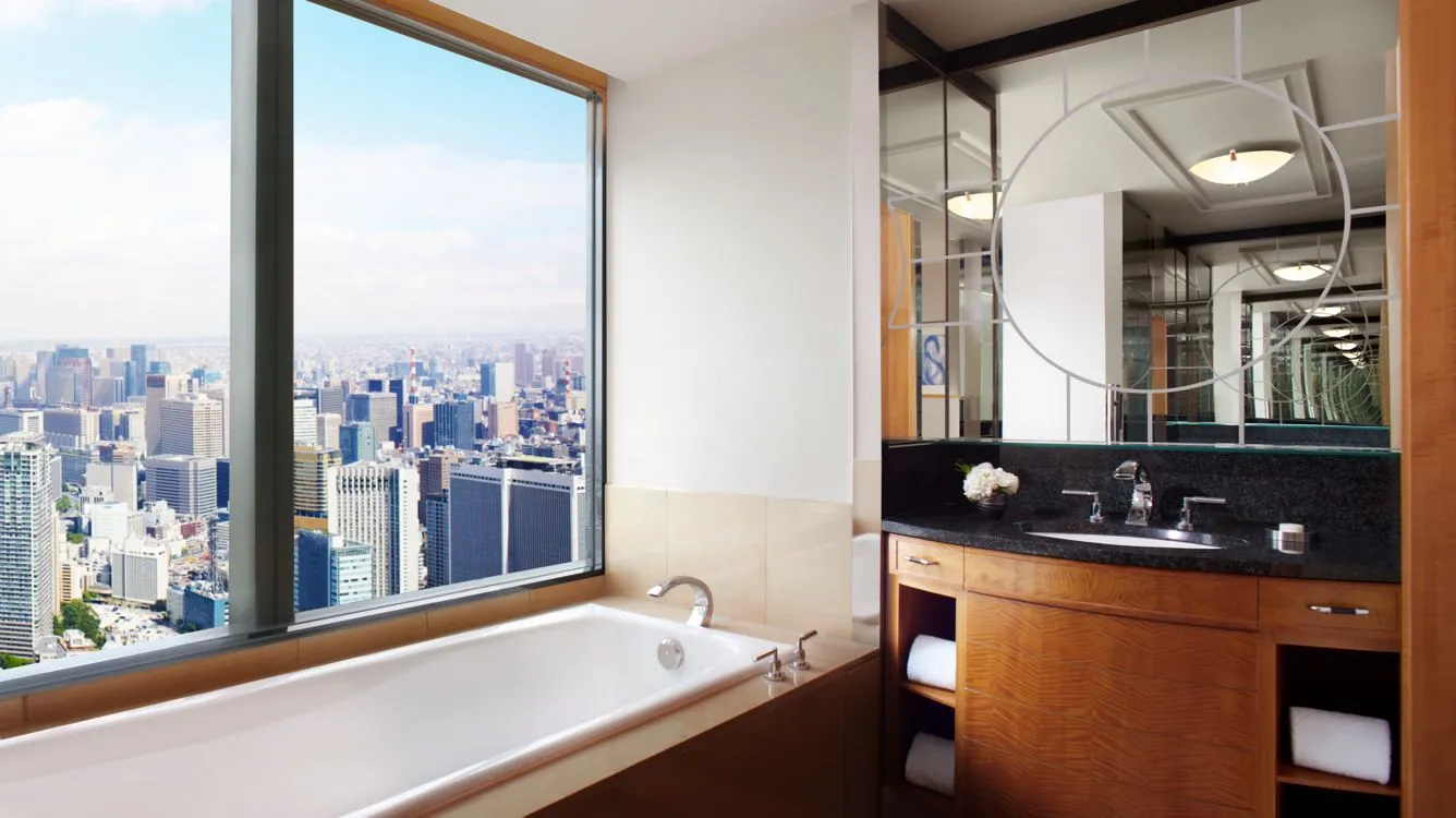 baño de lujo con tina, implementos de aseo personal y una ventana grande donde se va poder disfrutar de la vista a la ciudad