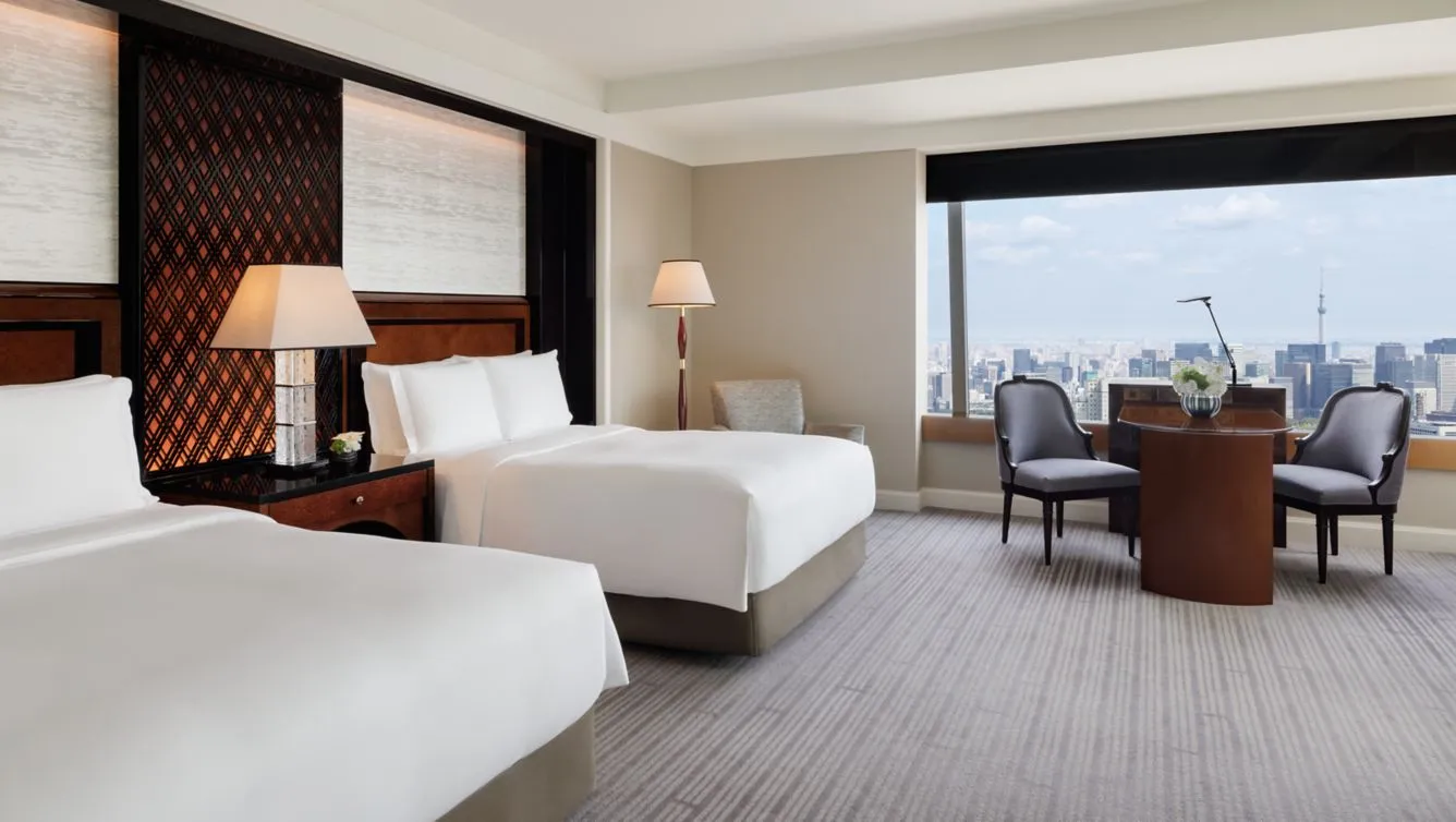 el hotel the ritz cartltlon cuenta con una habitación amplia con dos camas dobles, lamparas para una mejor iluminación, sillones y un ventanal con vista a la ciudad.