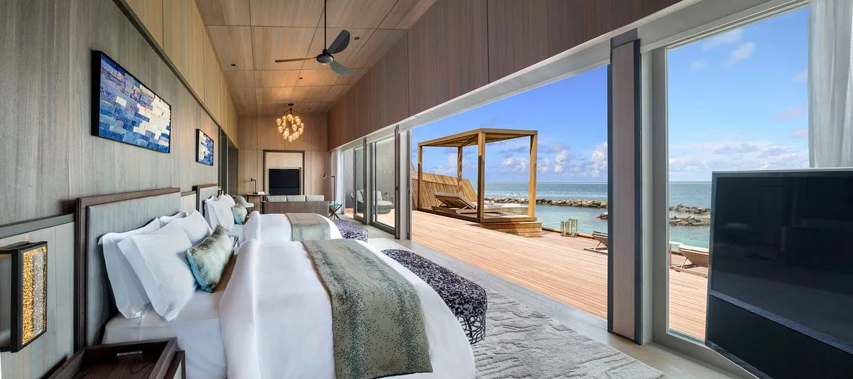 habitación grande con cama doble para 4 personas con televisor y un ventanal con balcón que conecta a la playa.