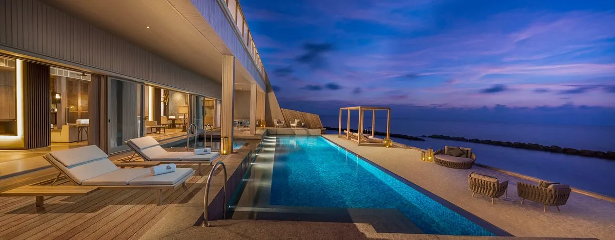 zona de piscina privada rodeada de sillas de descanso y con vista a la playa