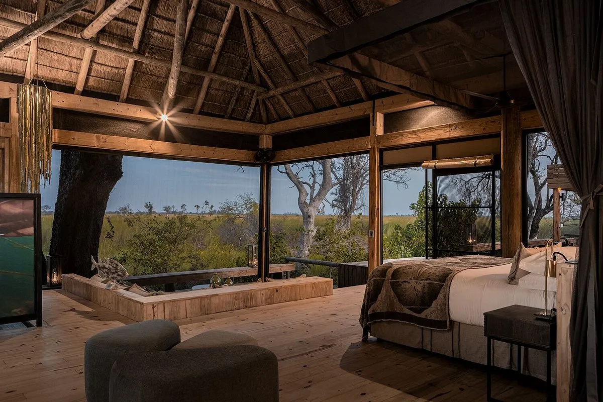 habitación para dos personas, con una cama para dos personas, asiento, en la parte de abajo en la misma habitación, hay un sillón espacioso con una mesa decorativa y un ventanal con vista al safari