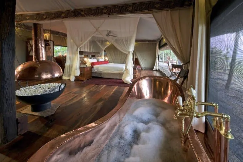 habitación para dos personas, con una cama amplia, asiento, al lado, en la misma habitación, hay una chimenea y una tina