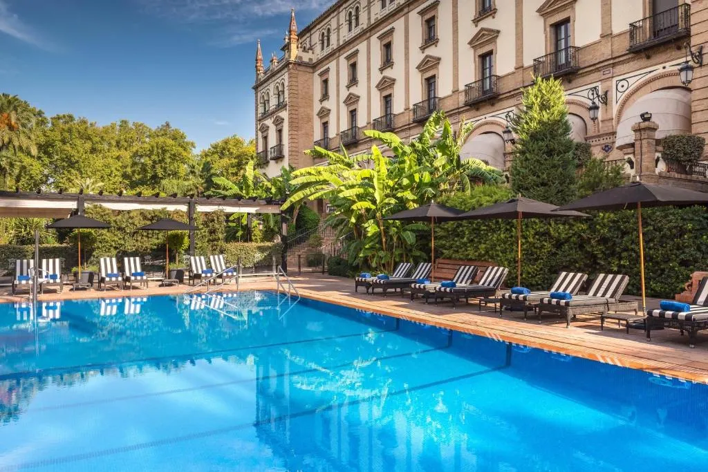 lujosa piscina rodeada de palmeras y árboles, con sillas cómodas para relajarse. El ambiente perfecto y tranquilo, para disfrutar de un día de descanso en un entorno natural.
