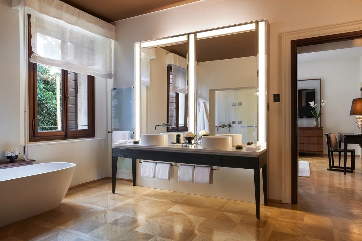Baño en el Hotel aman venice, con una elegante tina, un gran espejo con iluminación, lavamanos equipado con todos los implementos de aseo personal. Un lugar perfecto para relajarte y disfrutar.