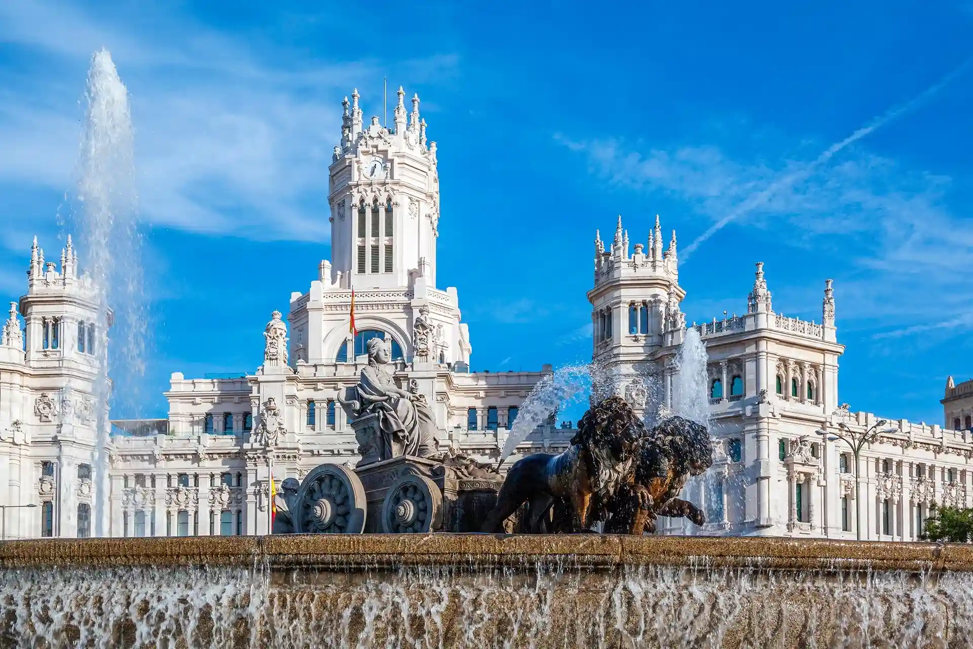 Vista de la Fuente de Cibeles en Madrid, con su imponente escultura y el agua fluyendo. Un lugar icónico, rodeado de edificios.