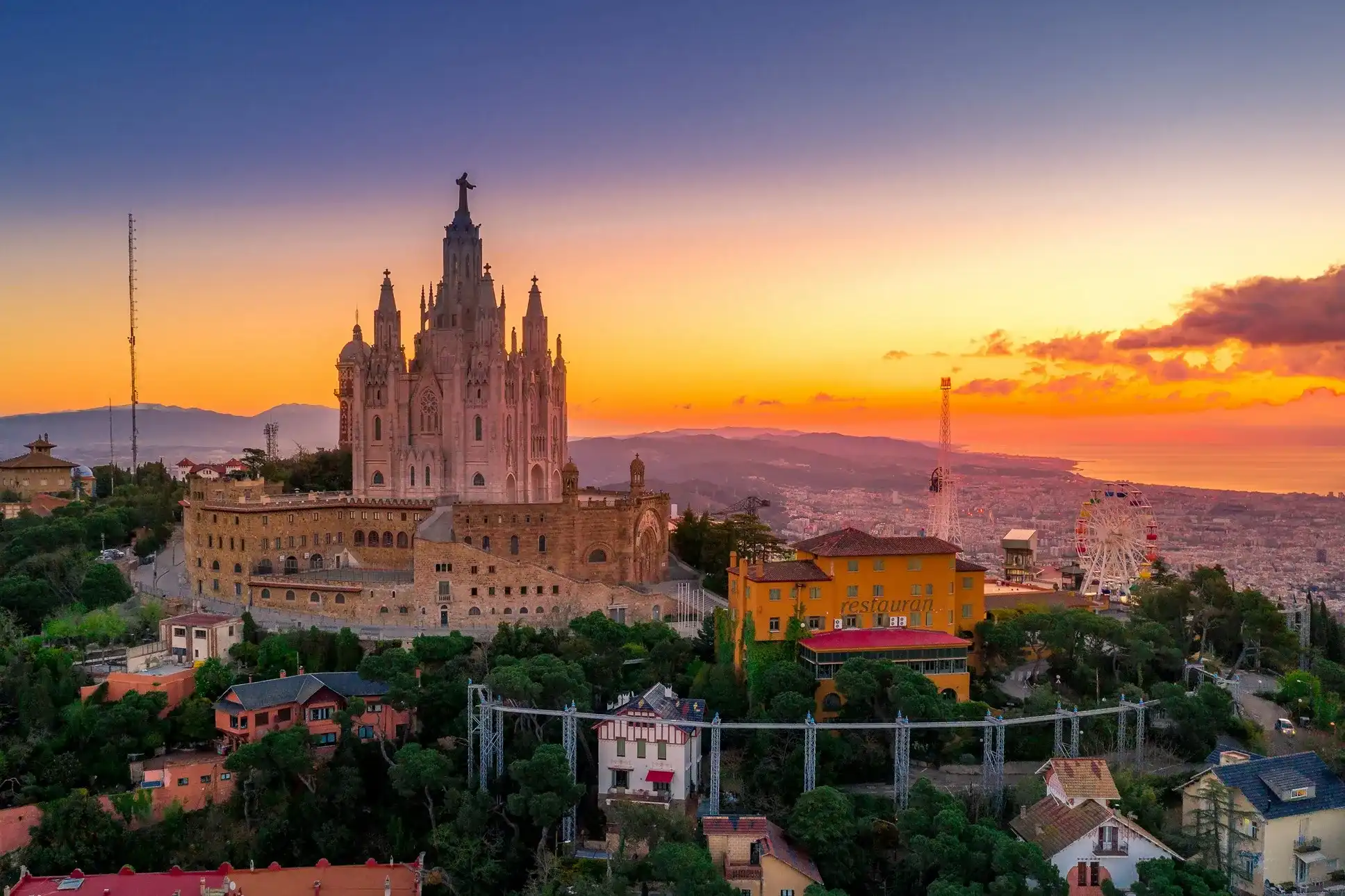 Basílica en España, rodeada de casas y restaurantes, en medio del atardecer para que puedas disfruta de la vista y de una buena comida.