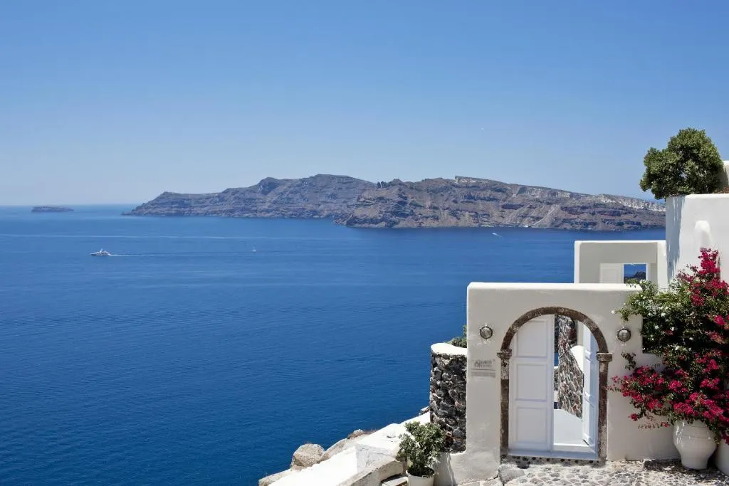 suite Canaves Oia de color blanco rodeado de jardines con vista al mar y a las montañas rocosas en Santorini.