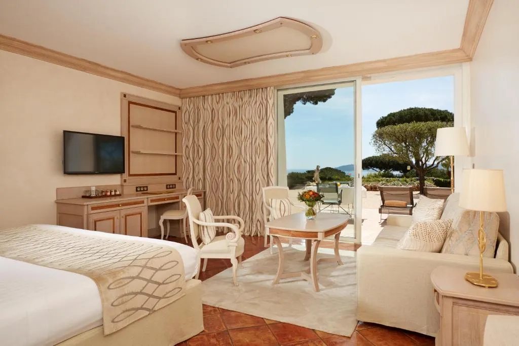 lujosa habitación con cama, sala y una ventana que conecta al balcón con una increíble vista al jardín.