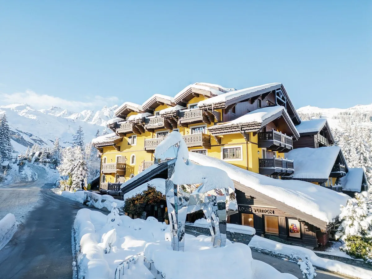 hotel Cheval Blanc Courchevel cubierta de nieve rodeada de montañas y arboles, perfecto para disfrutar de la vista en el invierno