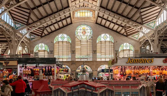 Plaza de mercado en una ciudad española, llena de puestos coloridos con productos frescos, Un lugar vibrante, ideal para disfrutar del ambiente local.