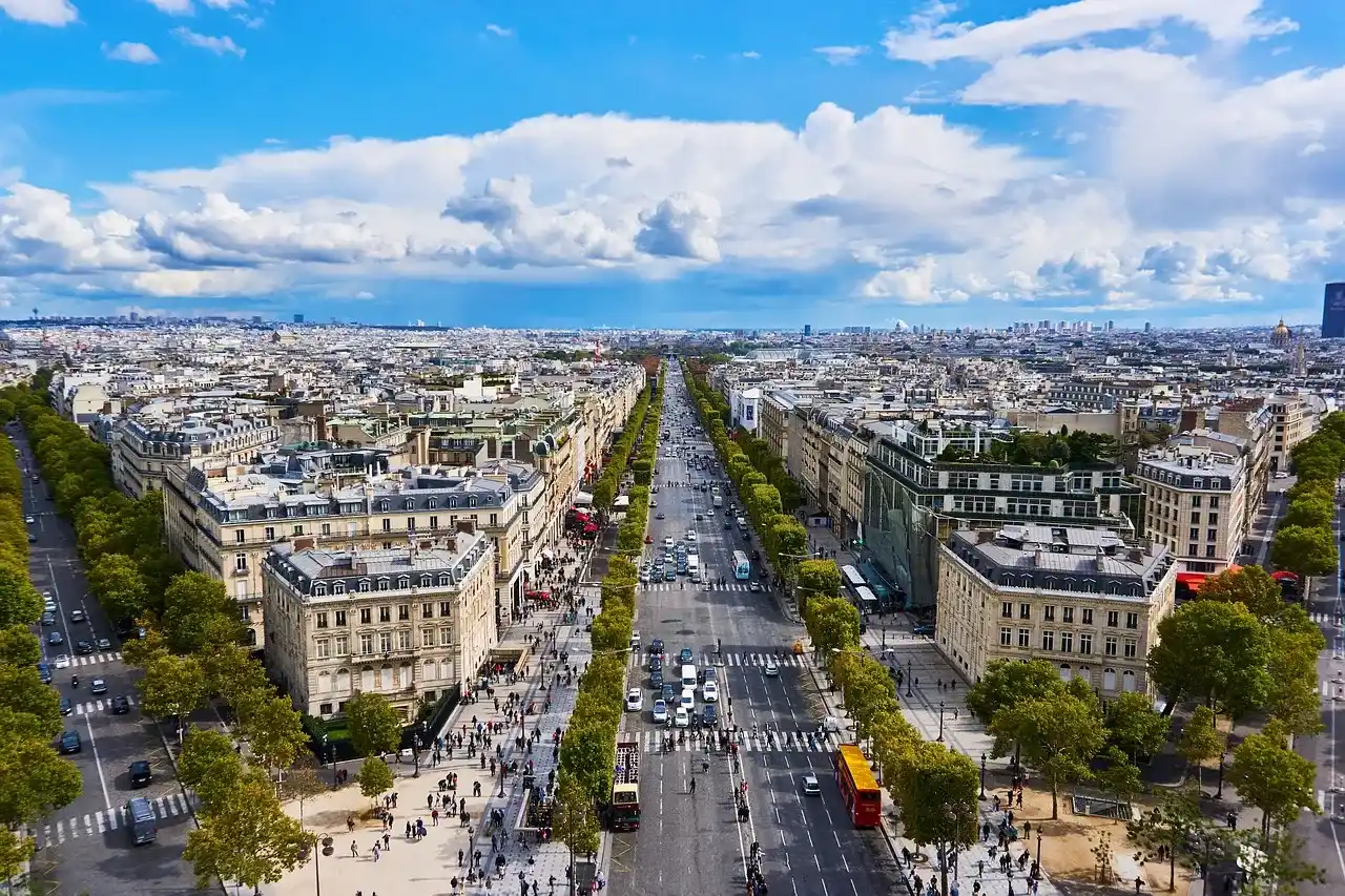 personas recorriendo las calles de Francia con sus espectaculares vistas de los edificios, rodeado de arboles.