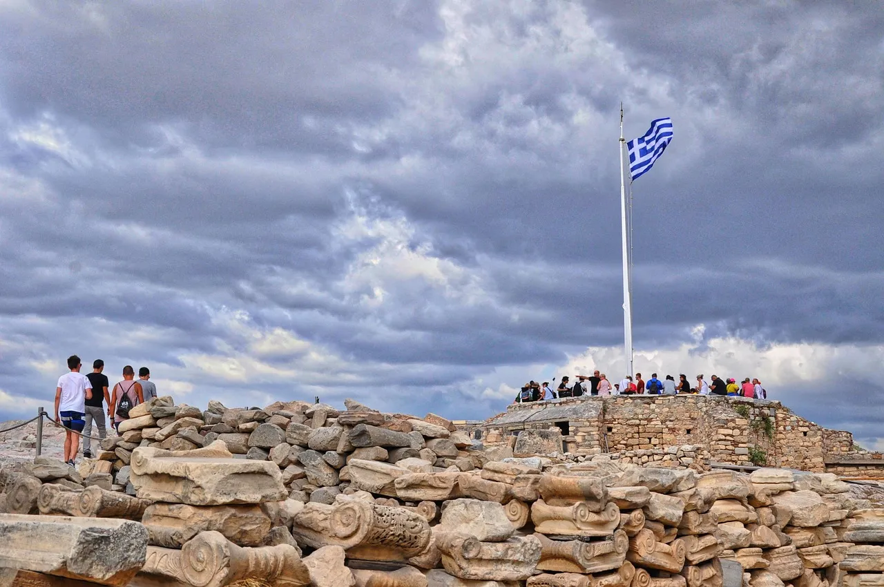 turistas caminando por un camino rocoso, llegando al mirador donde vas a poder disfrutar de las mejores vistas en Grecia.
