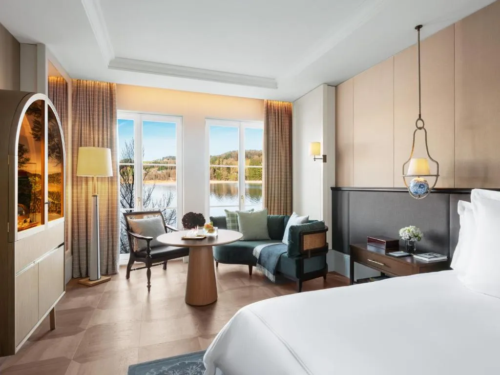 habitación amplia con cama para dos personas, una cómoda sala y un ventanal que ofrece una vista impresionante al mar.