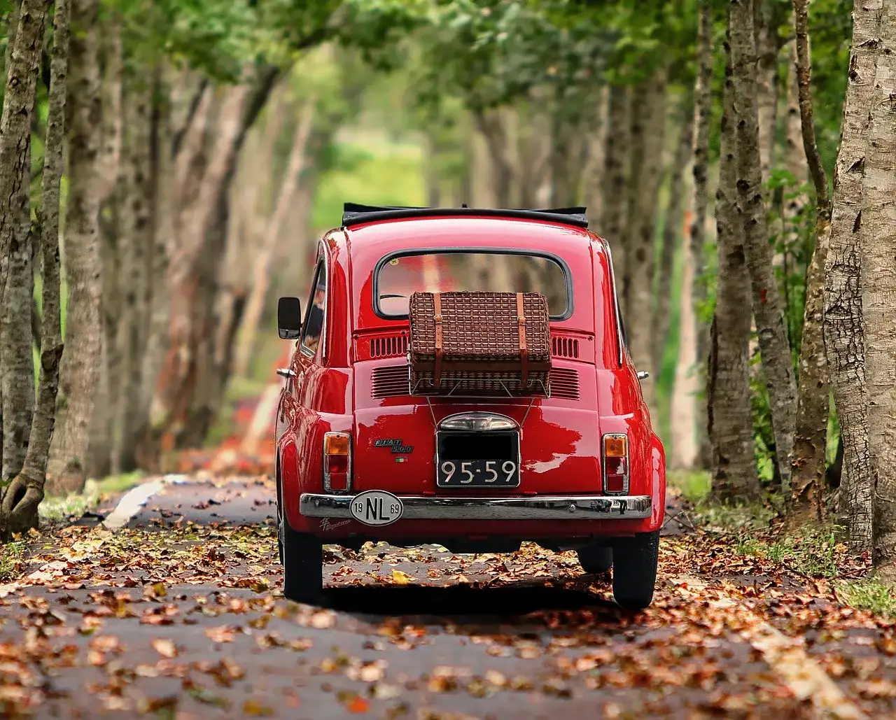 carro rojo recorriendo las calle rodeada de arboles en Italia.