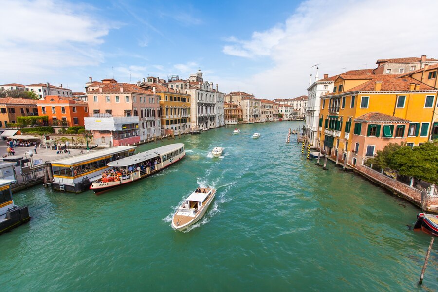 Explora la encantadora en Venecia, donde los edificios se reflejan en las aguas de sus canales y los yates navegan, creando un paisaje único.