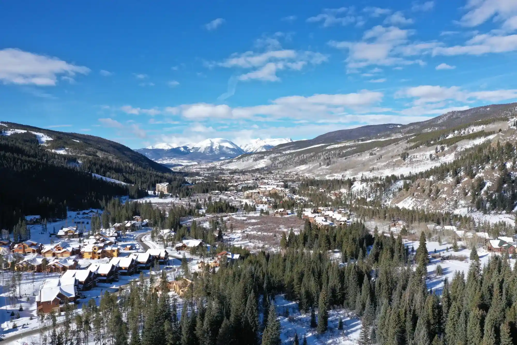 vista panorámica de las casas en las montañas rocosas cubiertas de nieve y rodeada de muchos arboles.