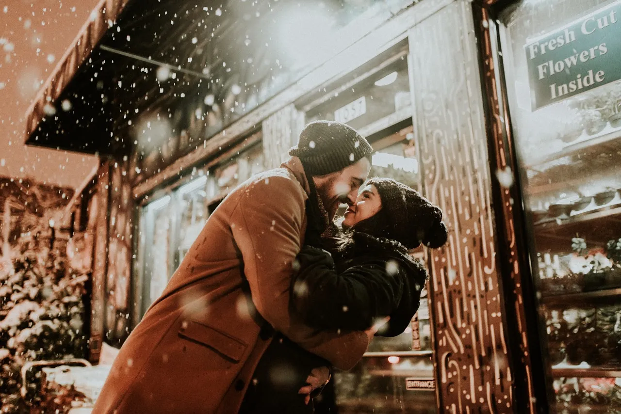 pareja abrazándose en medio de la nieve cayendo